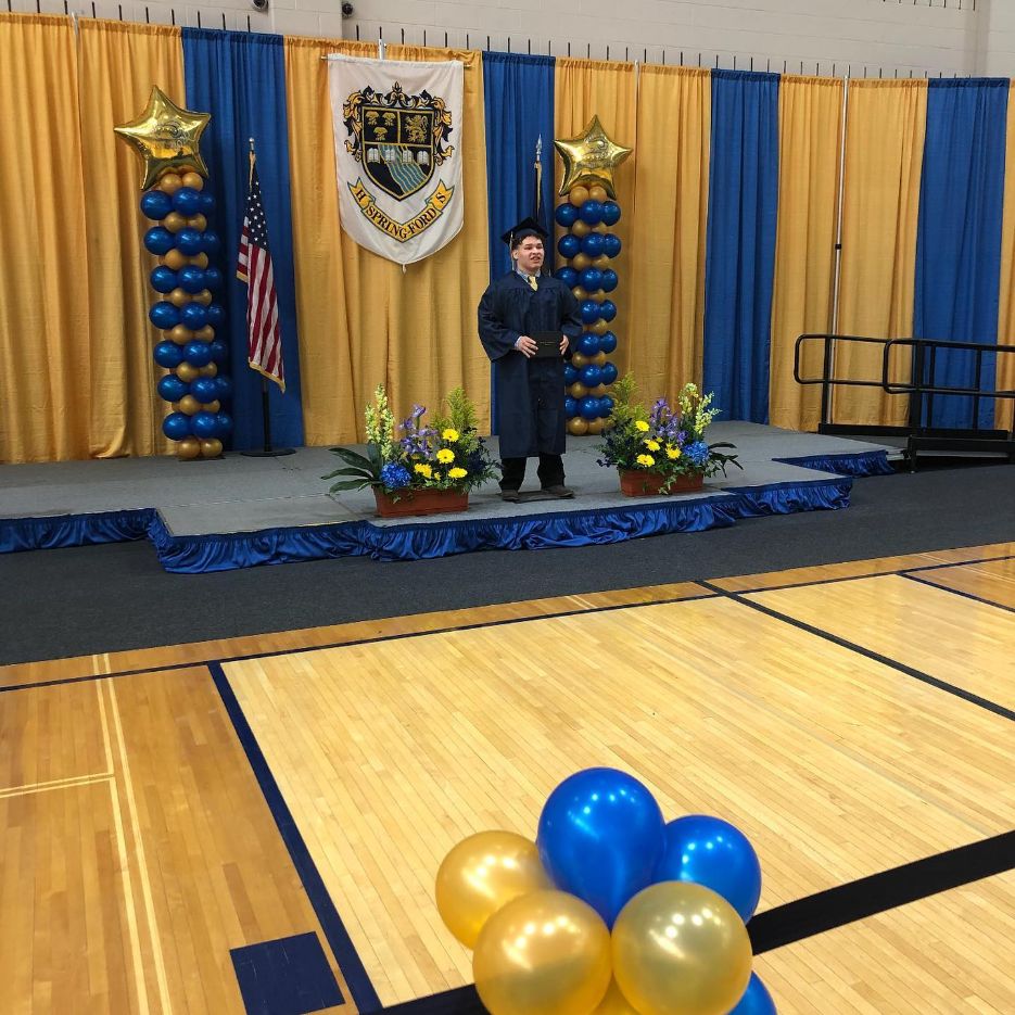 Louie standing on the Spring-Ford graduation stage in his cap and gown