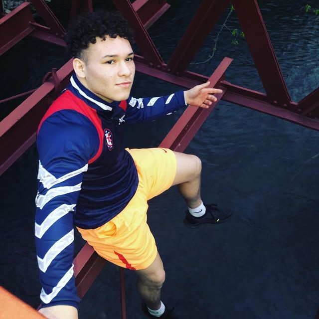 Louie Carbajal sitting on a red bridge structure